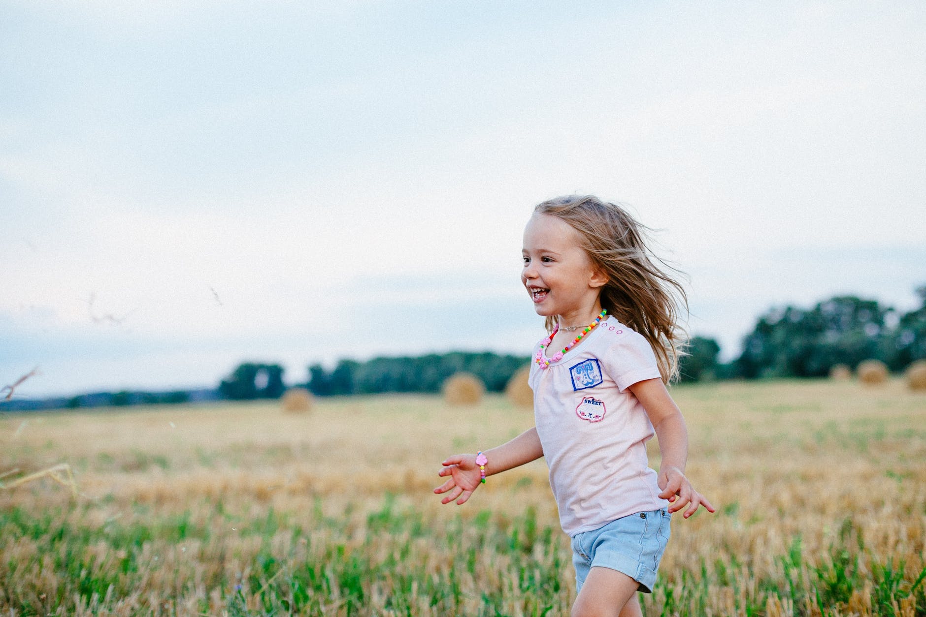 smiling girl running towards left on green field